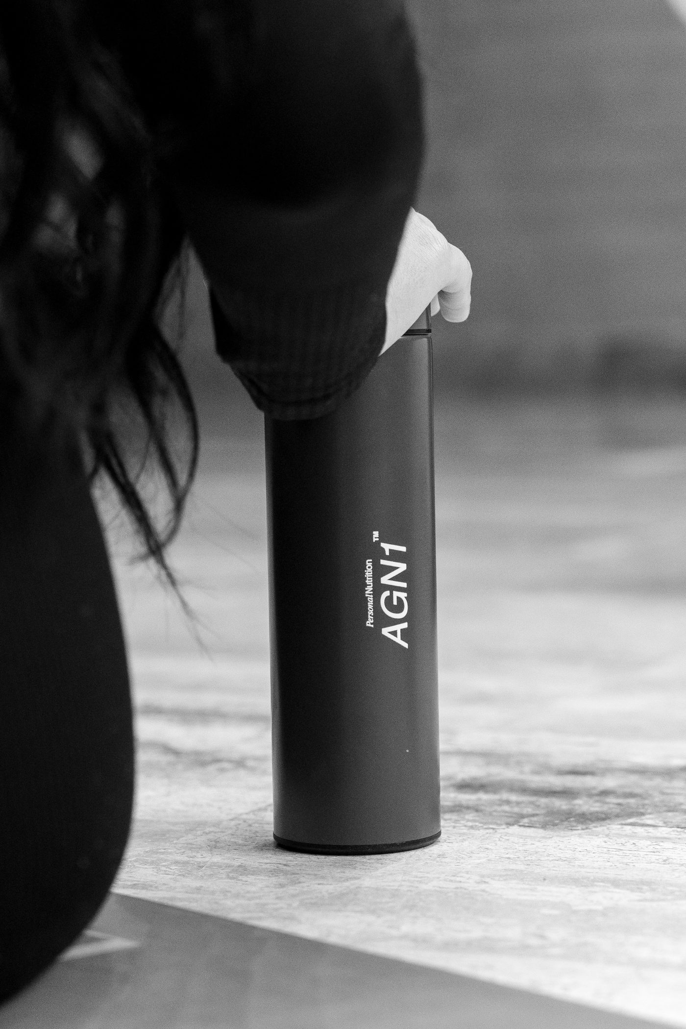 Black-and-white close-up of a hand resting on an AGN1 flask