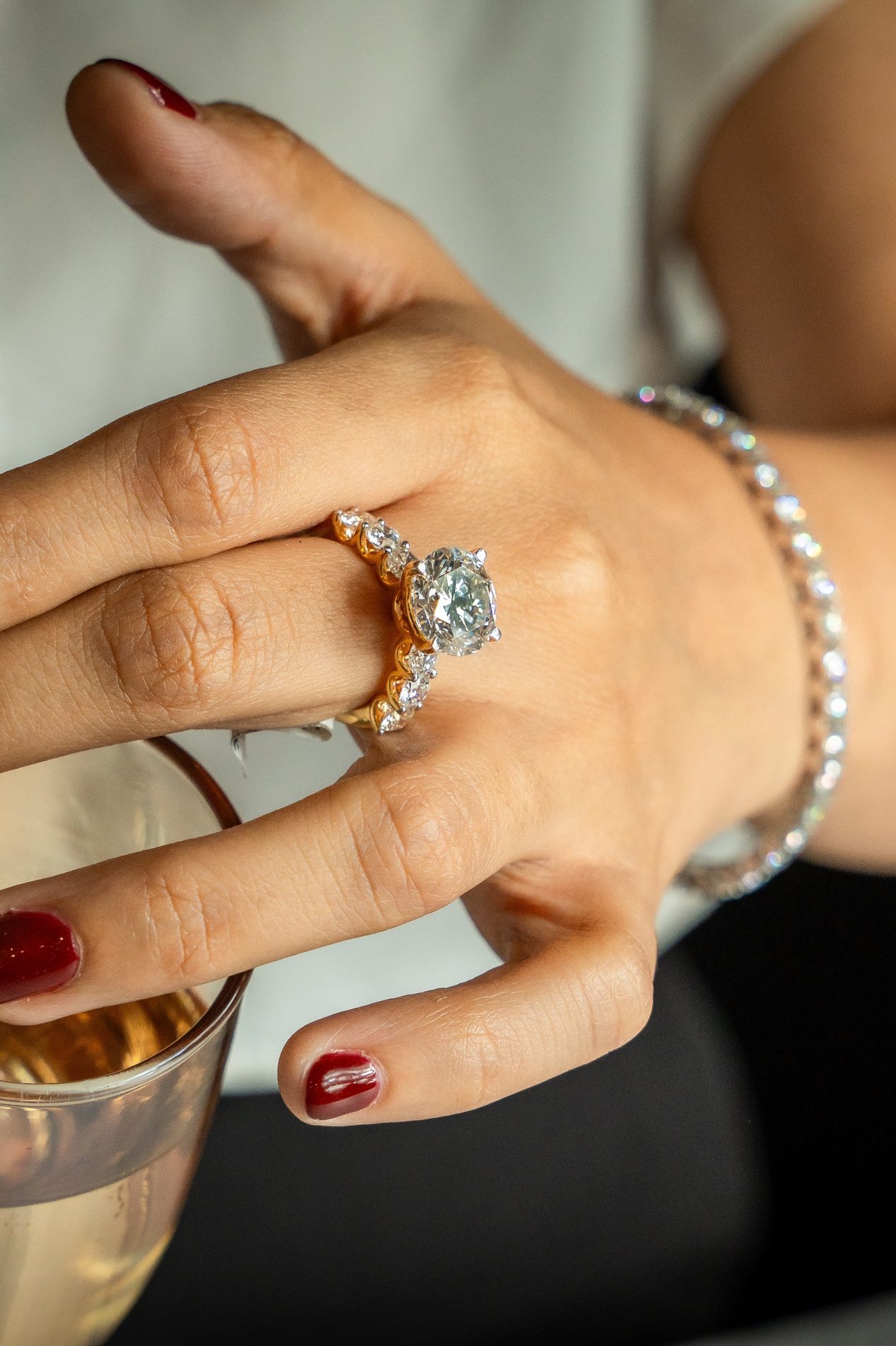 Hand wearing a large diamond ring and a pearl bracelet