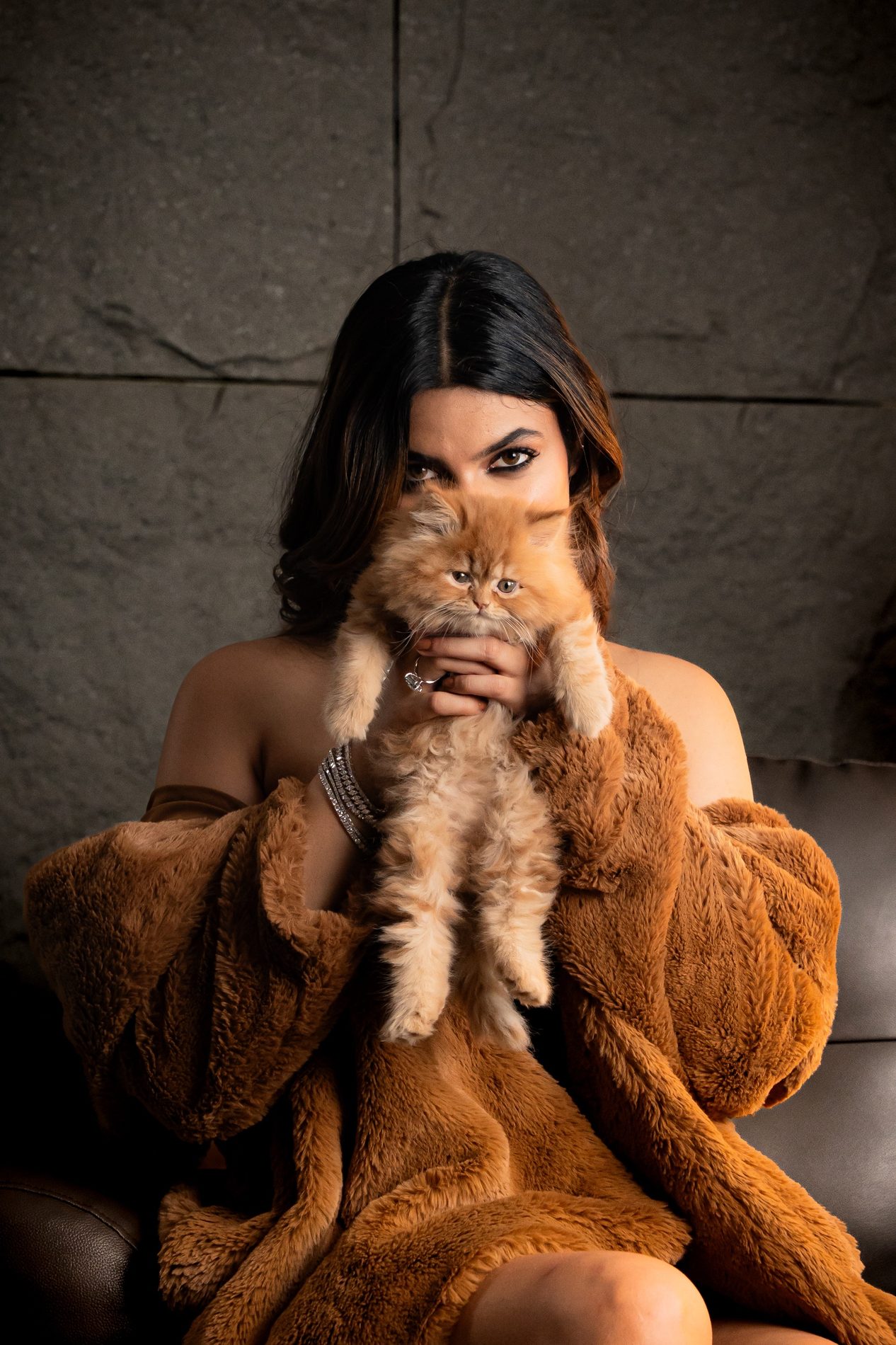 Woman holding an orange kitten in front of her face