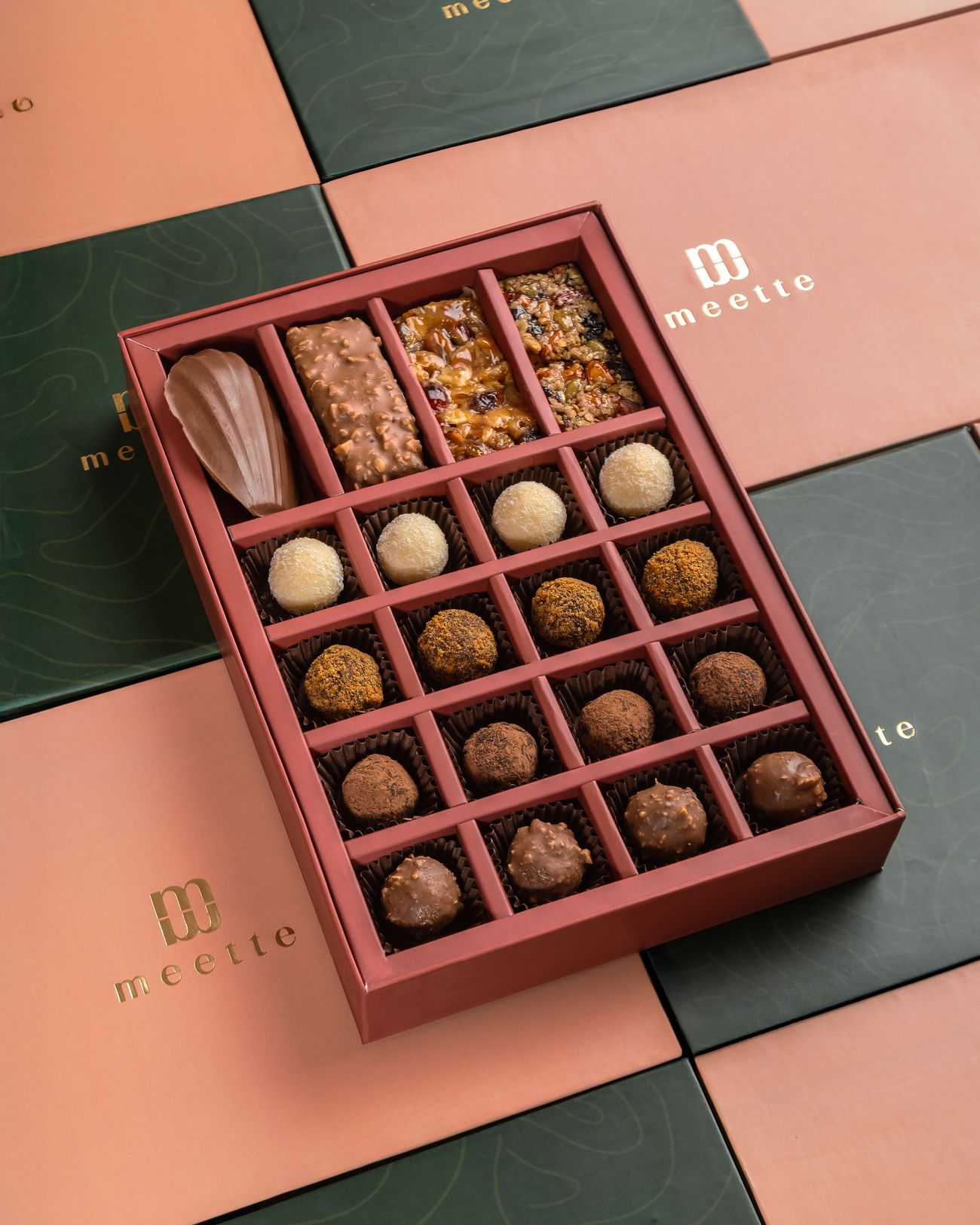 Open Meette box of assorted chocolates and bars on pink and green wrapping